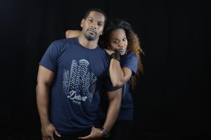 Man and woman wearing blue Detroit t-shirts with woman resting her arms on man