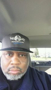 Man in car wearing black Pontiac hat